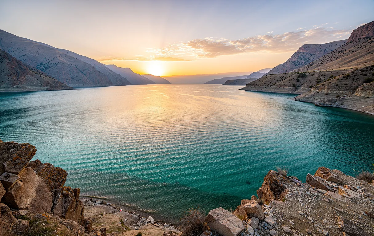 Le lac Van aux eaux turquoise bordé de montagnes rugueuses sous une lumière dorée au coucher du soleil.