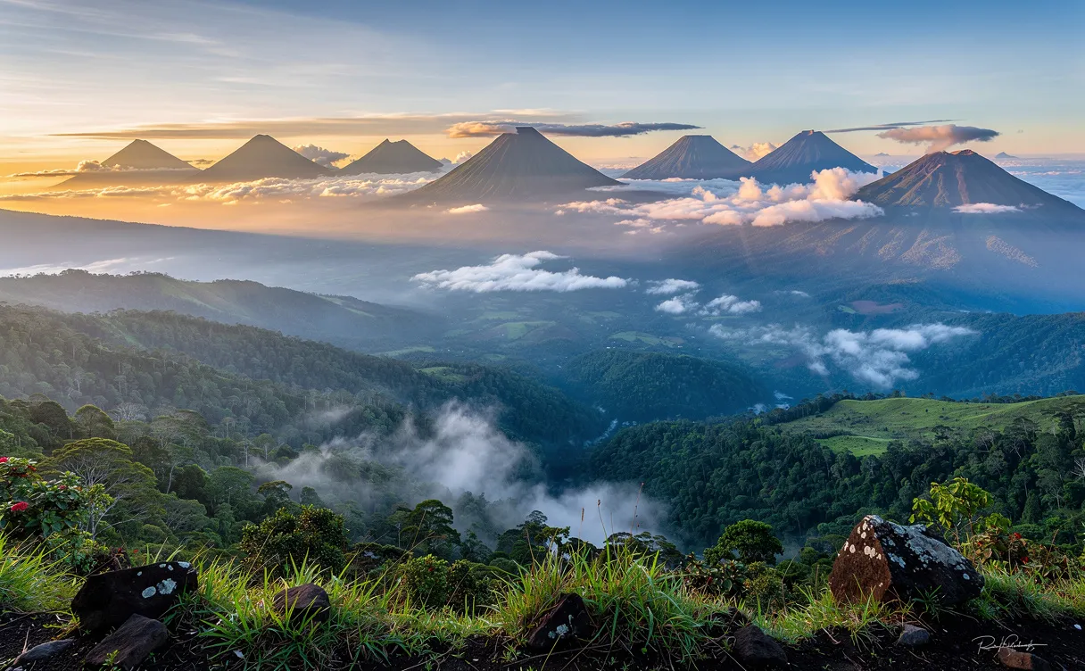 Vue panoramique de dix volcans mexicains s’élevant au-dessus de vallées verdoyantes et de forêts embrumées au lever du soleil, avec des sommets enveloppés de nuages et baignés de lumière dorée.