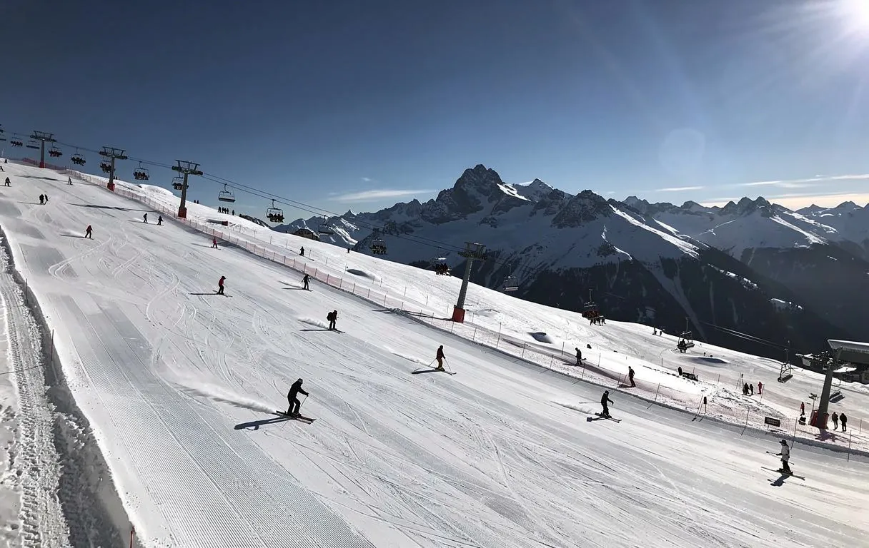 Vue d'une webcam montrant des skieurs sur les pistes enneigées de Saint-Lary sous un ciel bleu et ensoleillé.