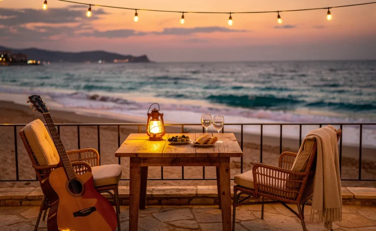 Terrasse en bord de mer méditerranéenne au coucher du soleil avec une guitare posée sur une chaise, lumière dorée et vagues calmes.