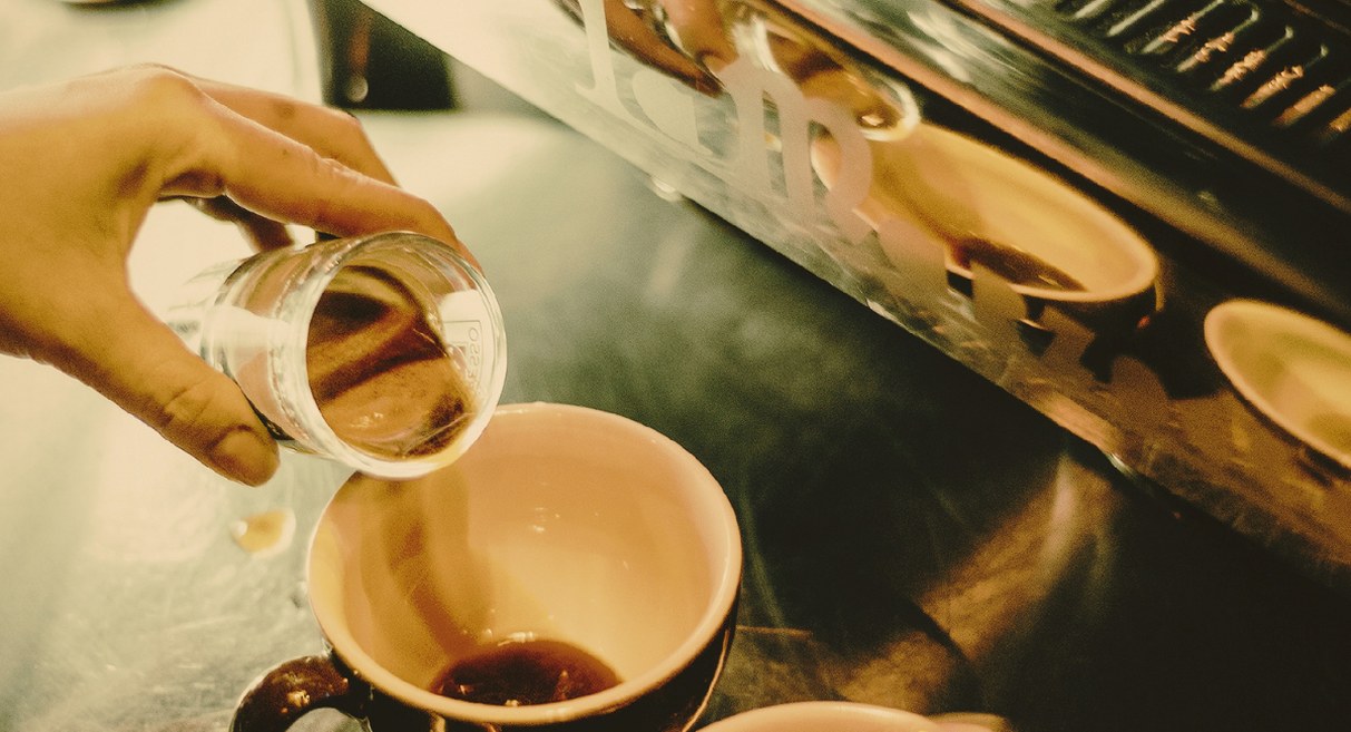 Barista versant un expresso dans une tasse au comptoir d'un coffee shop artisanal