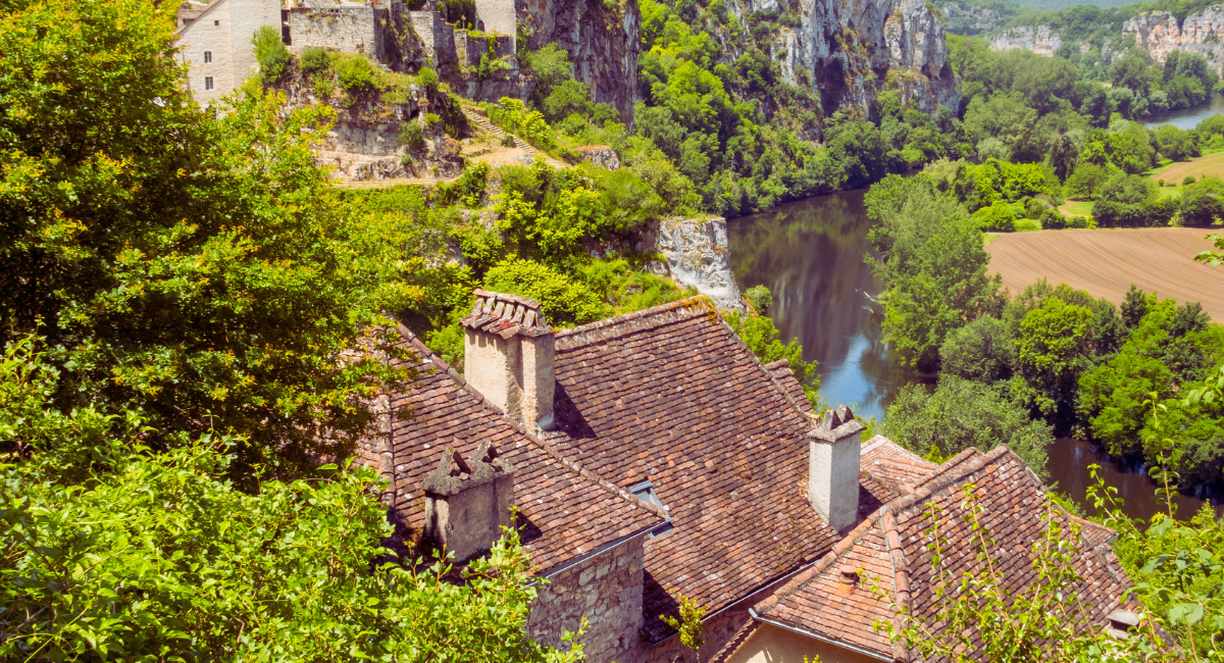 Village médiéval perché sur une falaise calcaire avec vue sur la rivière et les champs verts en Occitanie
