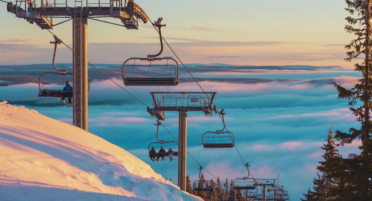 Télésiège de station de ski au-dessus des nuages avec vue panoramique au coucher de soleil
