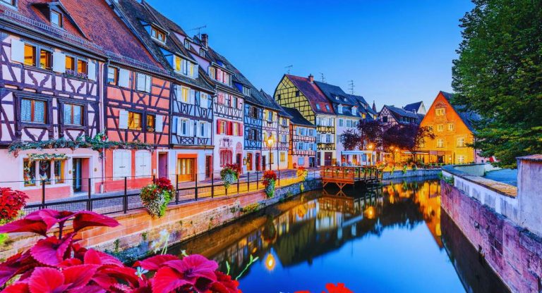 Maisons à colombages colorées illuminées au bord d'un canal en Alsace au crépuscule
