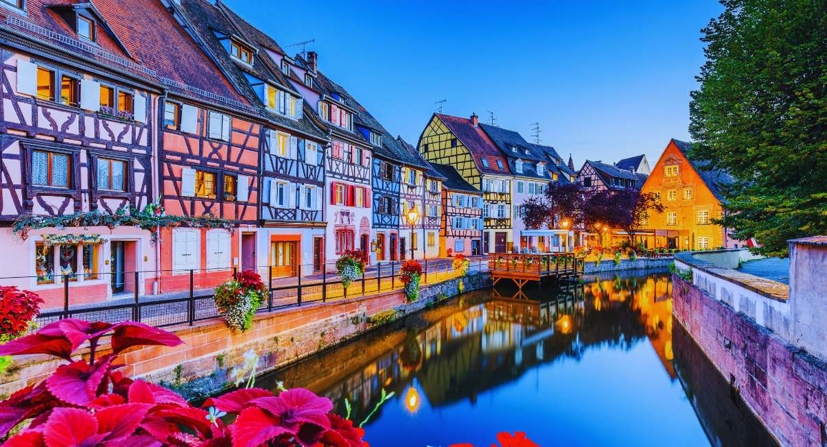 Maisons à colombages colorées illuminées au bord d'un canal en Alsace au crépuscule